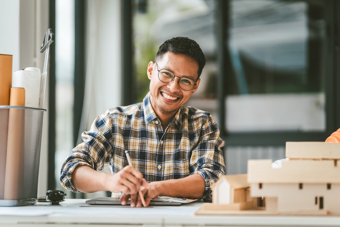 Filipino architect reviewing blueprints and house model
